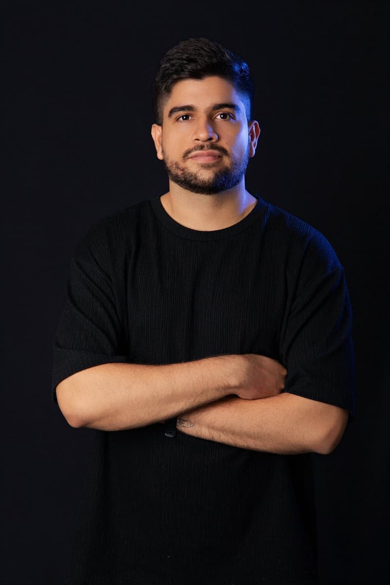 Juan Camilo Rojas facing the camera with arms crossed, black background and blue light
